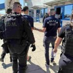 Charles Francis Kaufmann mentre parte dalla Grecia viene scortato dalla polizia in arresto