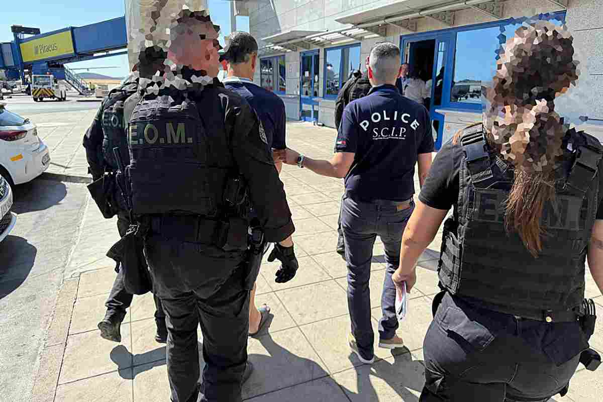 Charles Francis Kaufmann mentre parte dalla Grecia viene scortato dalla polizia in arresto