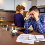 uomo disperato con le mani in testa e dietro di lui una donna