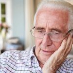 uomo anziano preoccupato con una mano su una guancia