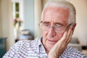 uomo anziano preoccupato con una mano su una guancia