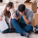 uomo e donna disperati seduti sul pavimento con dietro degli scatoloni