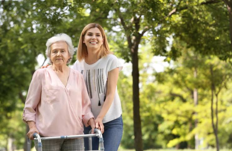 anziana al parco con il girello accompagnata dalla badante