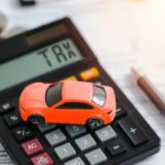 auto in miniatura sopra ad una calcolatrice e ad un foglio