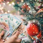 euro in mano e albero di natale