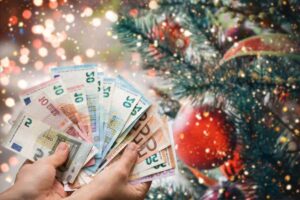 euro in mano e albero di natale