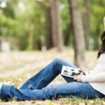 donna in un bosco seduta ai piedi di un albero