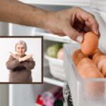 uomo che prende un uovo dalla porta del frigo e donna che dice no con le mani incrociate a x