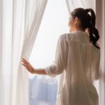donna dalla finestra che apre le tende