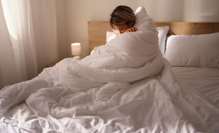 donna a letto avvolta nel piumone