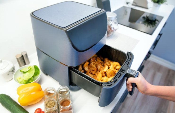 persona che cucina delle patate nella friggitrice ad aria
