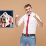 uomo che esulta e nel riquadro una casetta in miniatura