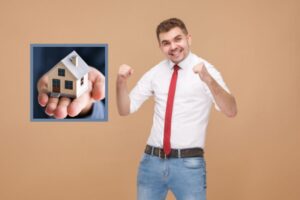 uomo che esulta e nel riquadro una casetta in miniatura