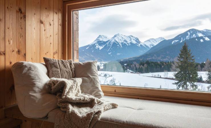 divano con cuscini e coperta davanti a finestra