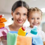 mamma e bambina che sorridono con dei detersivi in mano per fare le pulizie