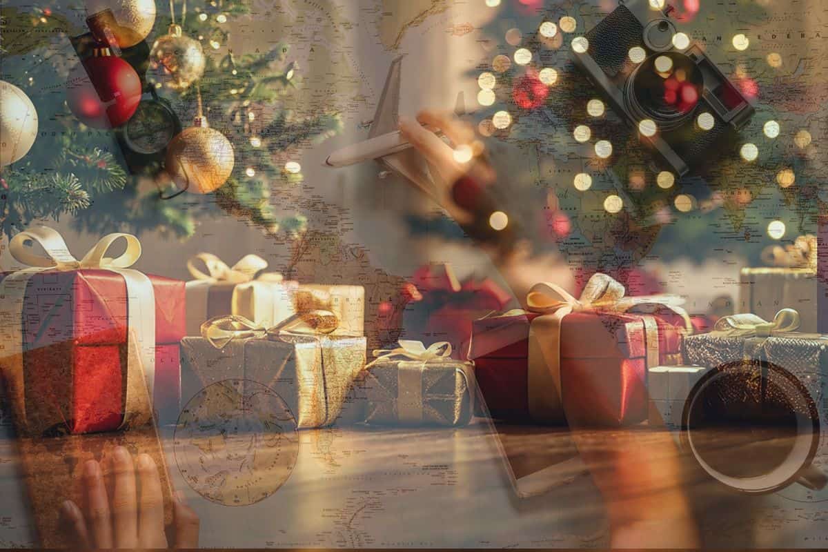 sfondo albero natale con regali sfocato cartina geografica mano che sposta un modellino aereo, macchina fotografica, passaporto
