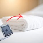 asciugamano sul letto con freccia che lo indica e pinze che tengono un microchip