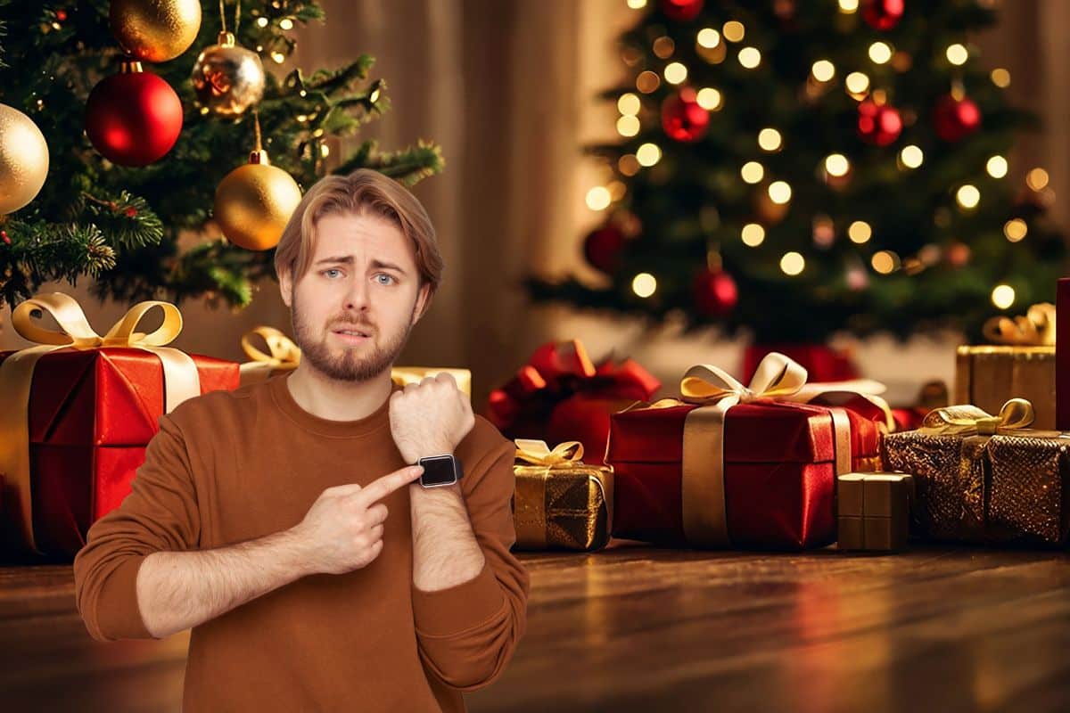 regali natale sotto albero con ragazzo che guarda orario su orologio polso
