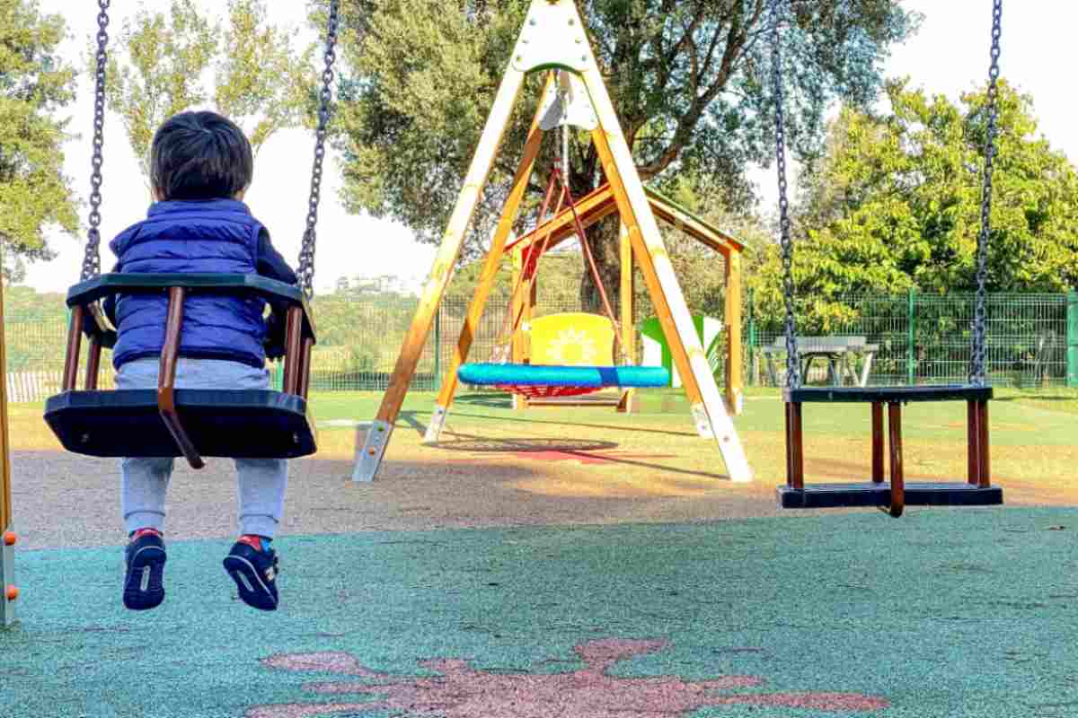 bambino sull'altalena al parco giochi
