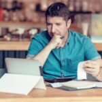 uomo davanti al computer che controlla dei fogli