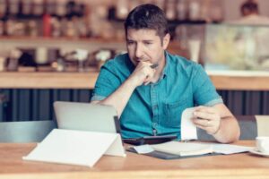 uomo davanti al computer che controlla dei fogli