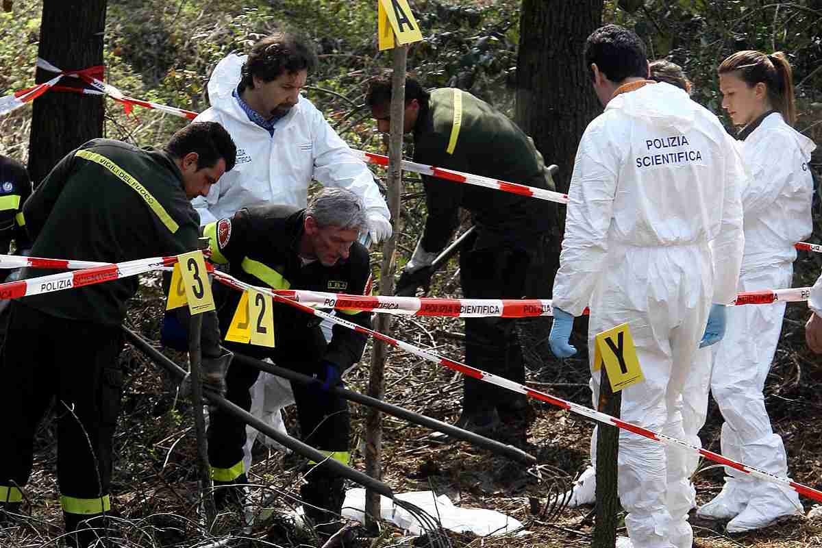 Forze dell'ordine camminano dentro al perimetro segnato dal cordone con il corpo del piccolo Tommy coperto