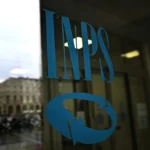 Logo INPS sulla vetrata di ingresso dell'Istituto Nazionale di Previdenza Sociale.